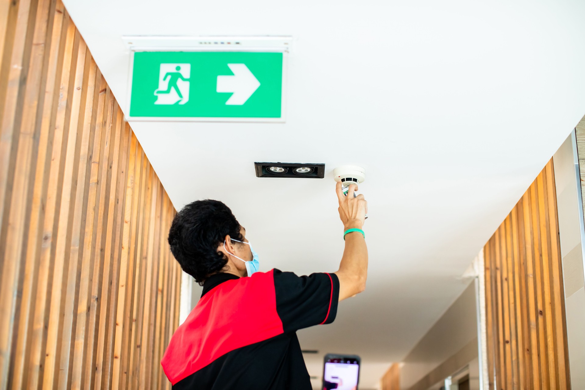 The technician is using smoke spray to check smoke detector of fire alarm system.